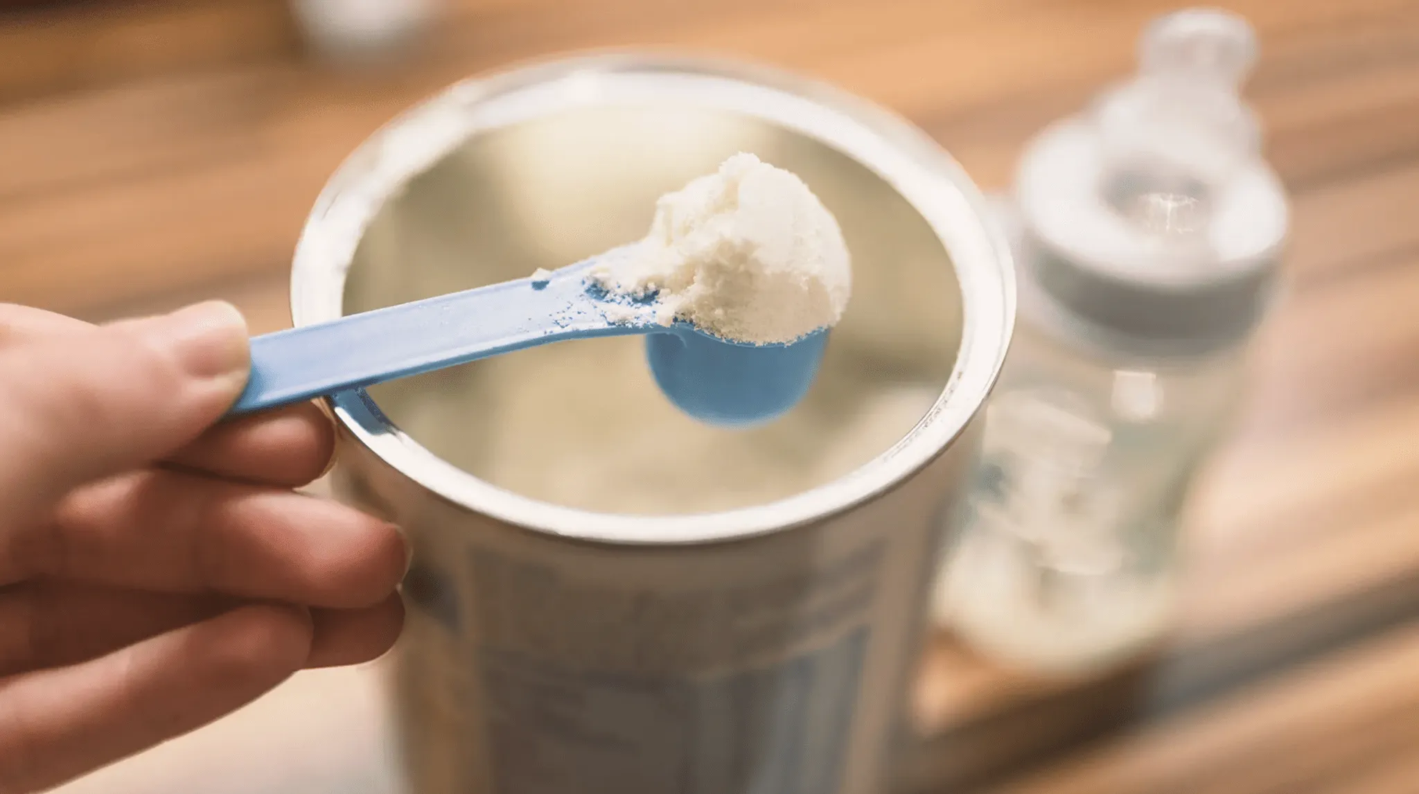 A spoonful of instant formula being taken out of a larger container